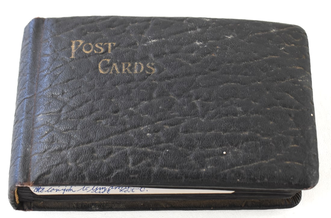 LEATHER POSTCARD BOOK W/ 71 VINTAGE POSTCARDS: A leather postcard book with a collection of approximately 71 vintage postcards from scenes across America. The postcard book measures 5" H x 8" W x 2" D.