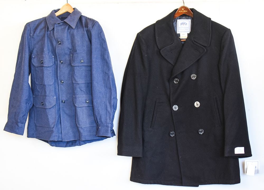 NEW OLD STOCK NAVY ISSUED BLACK WOOL PEACOAT & HEAVY WOOL SHIRT: A pair of new-old-stock Navy issued heavy wool button-up shirt and a black wool peacoat sized a 44L and measuring approx. 23" pit-pit and 39" back collar-hem.