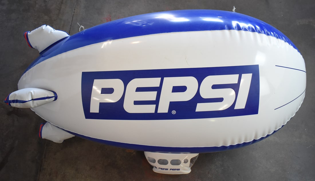 PEPSI PROMOTIONAL INFLATABLE BLIMP: Promotional blimp for the soda company Pepsi. Blimp is from a promotional campaign in the late 20th century in gas stations. When inflated the blimp measures approx. 26" H x 48" W x 18" D.