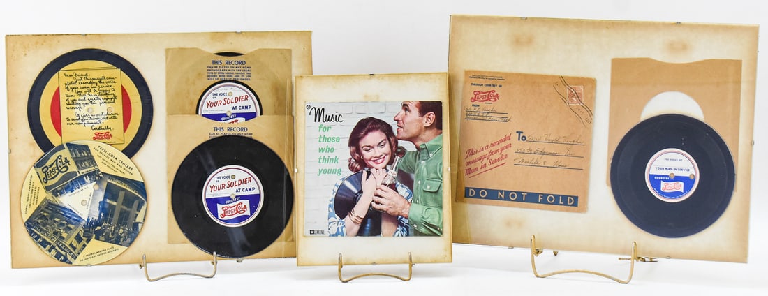 FRAMED PROMOTIONAL PEPSI "THE VOICE OF YOUR SOLDER AT CAMP" RECORDS & MORE: A pair of framed record displays showing the Pepsi promotional program "The Voice of Your Soldier At Camp", a World War II promotion where Pepsi would record the voices of soldiers on records to send