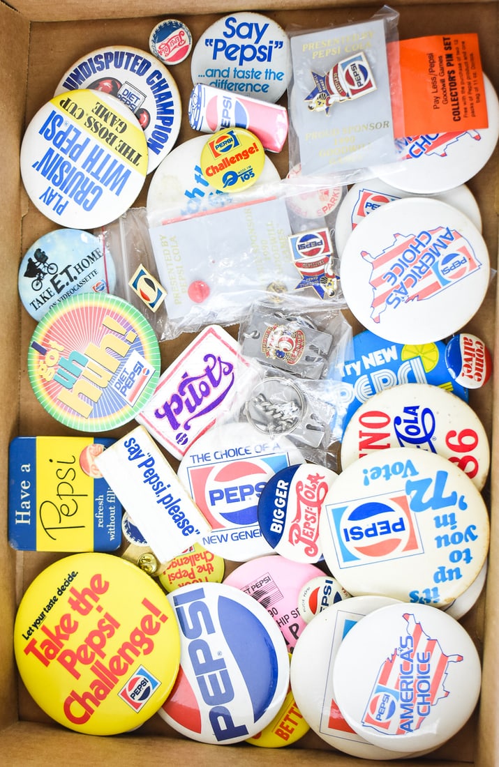 LOT OF PEPSI BUTTONS, PINS & KEYCHAINS: A Variety of Pepsi branded buttons circa 1970 - 1980. The largest button measures approximately 4" H x 4" W x 0.5" D.