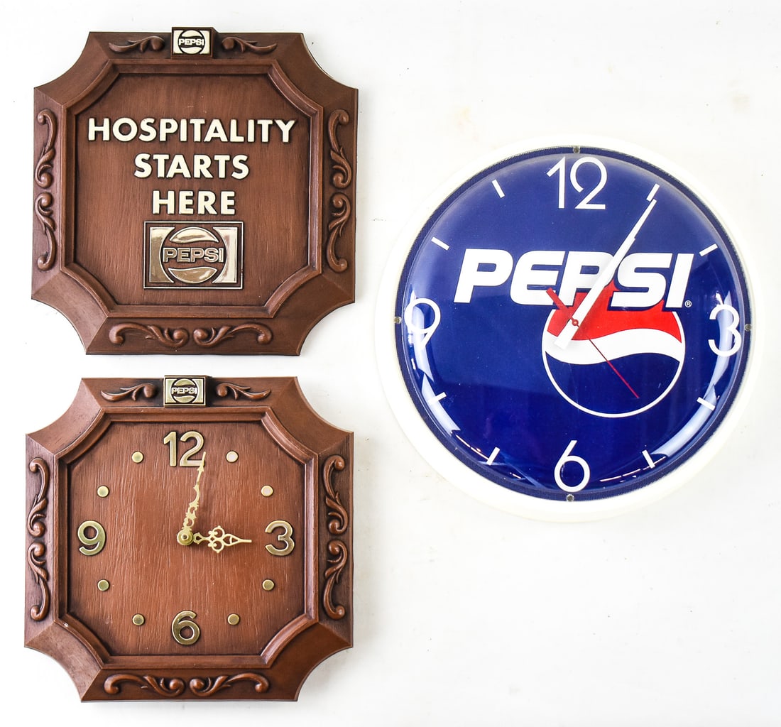 SET OF TWO PEPSI-COLA WALL CLOCKS & ONE SIGN: Includes one round clock, one faux wood square clock and one sign matching the square clock that states "Hospitality Starts Here". All three pieces are plastic. The round clock measures 14" H x 14" W 