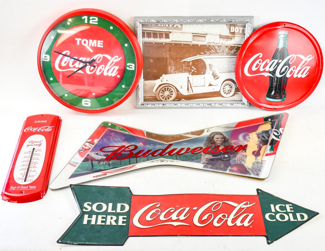 LOT OF COCA-COLA SIGNS & ONE BUDWEISER BOWTIE MIRROR: Includes a 2006 Budweiser bowtie mirror, one round metal Coca-Cola sign, one arrow shaped metal Coke sign, one metal Coke wall thermometer, one plastic Coke wall clock, and a framed photo of an old co