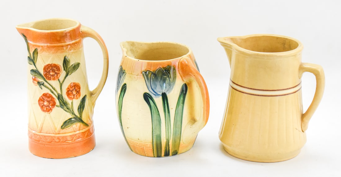 MID CENTURY PITCHERS: ROSEVILLE "TULIPS", "WILD ROSES", AND RED WING SAFFRON WARE: This lot includes: The Roseville Pottery Company "Tulips" and "Wild Roses" pitchers, early 20th century; and a saffron ware pitcher by The Red Wing Stoneware Company circa 1910. The largest item measu
