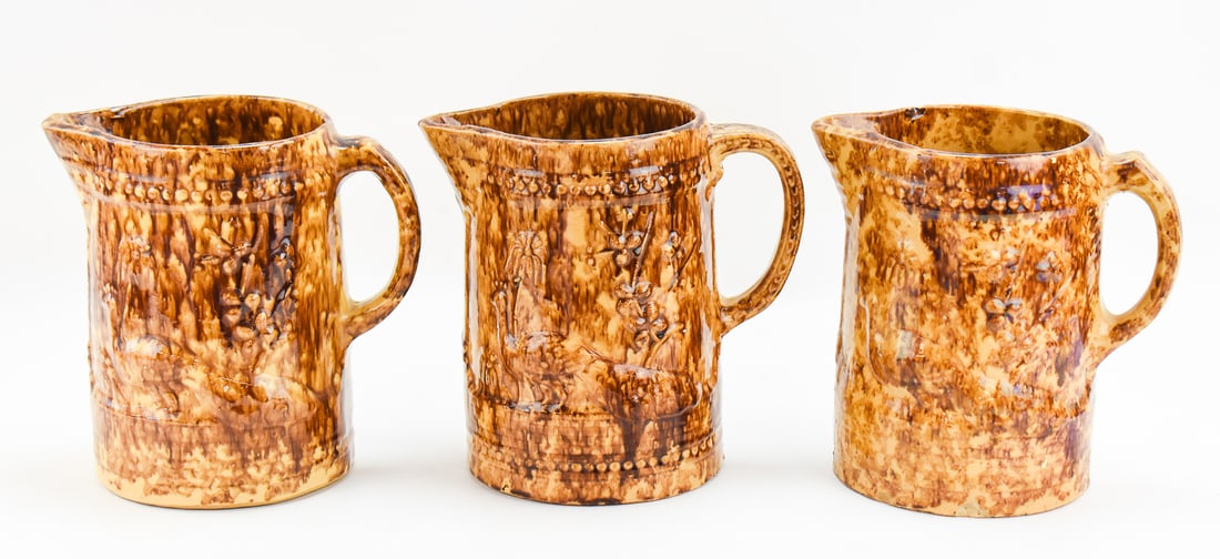 THREE AMERICAN 'PEACOCK AND PALM TREE' ROCKINGHAM STYLE PITCHERS: This lot includes three American 'Peacock and Palm Tree" Rockingham-glazed pitchers, from late 19th century. The items measure approx. 8.5" H x 9" W x 6" D.