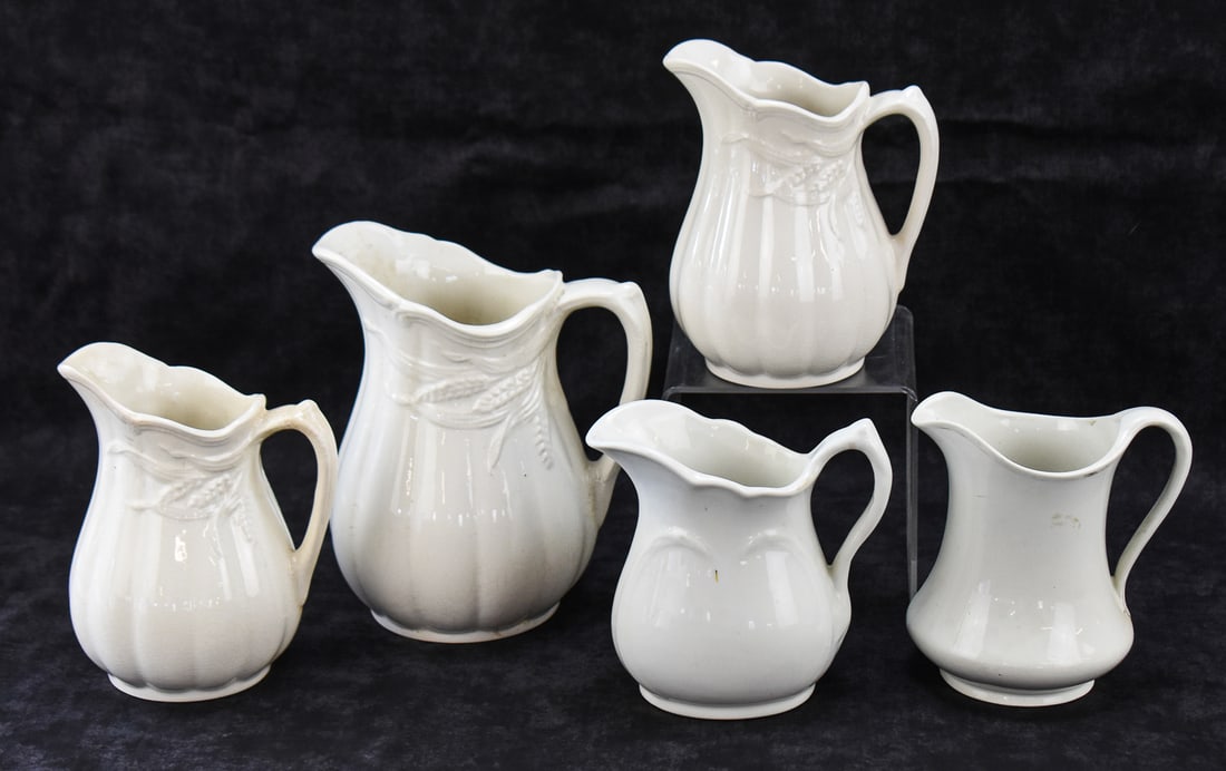 ROYAL CROWNFORD AND BAKEWELL BROTHERS WHITE IRONSTONE PITCHERS: This lot includes four Arthur George for Royal Crownford "Wheat" English ironstone pitchers in various sizes, from early 20th century; and one Bakewell Brothers pitcher. The largest item measures appr