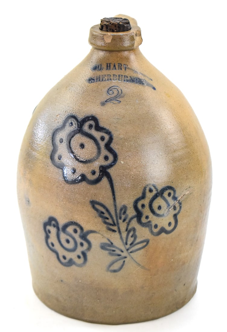 CHARLES HART TWO-GALLON STONEWARE JUG: A marked Charles Hart (Sherburne, NY) two-gallon jug featuring a cobalt flower motif, from between 1858-1866. The item measures approx. 13.5" H x 8" W x 8" D.