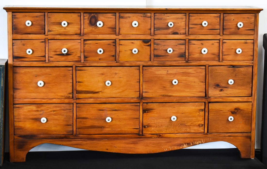 AMERICAN GENERAL STORE PINE APOTHECARY CABINET: An American general store pine apothecary cabinet with 22 drawers outfitted with white porcelain knobs, from mid 19th century. The item measures approx. 29" H x 48" W x 8" D.