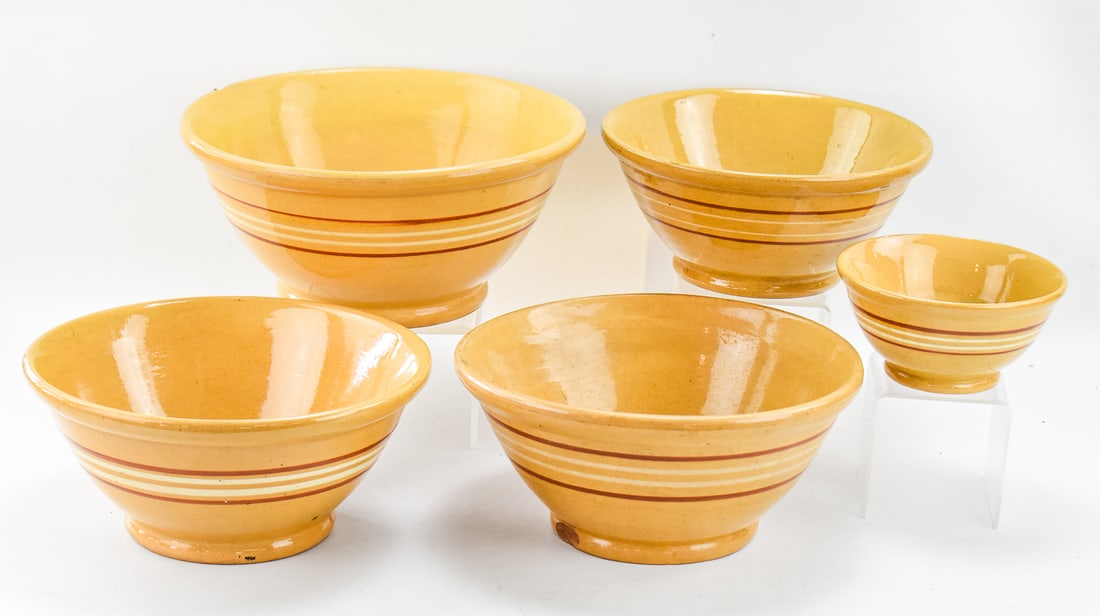 ASSORTMENT OF FIVE BANDED YELLOW WARE BOWLS: This lot includes five assorted yellow ware bowls decorated with colored banding, from early-mid 20th century. One of the bowls is smaller in size, and the other four of them are larger mixing or