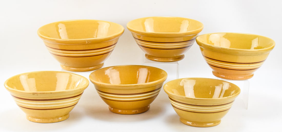 ASSORTMENT OF SIX LARGE BANDED YELLOW WARE BOWLS: This lot includes six assorted yellow ware bowls decorated with multi-colored banding, from early-mid 20th century. The largest bowl measures approx. 5.5" H x 11.5" W x 11.5" D.