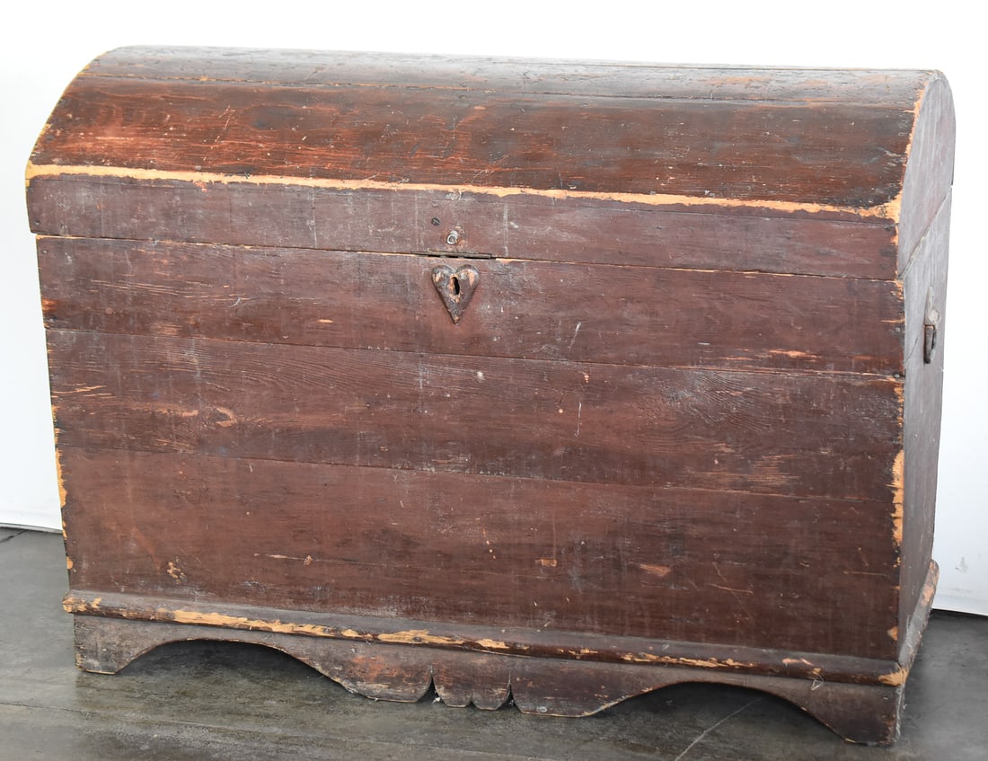 WOODEN DOME TOP BLANKET CHEST: A wooden dome-top blanket chest featuring a heart shaped keyhole, interior glove box, and a stained wood finish; from the 19th century. The item measures approx. 32" H x 43" W x 24" D.