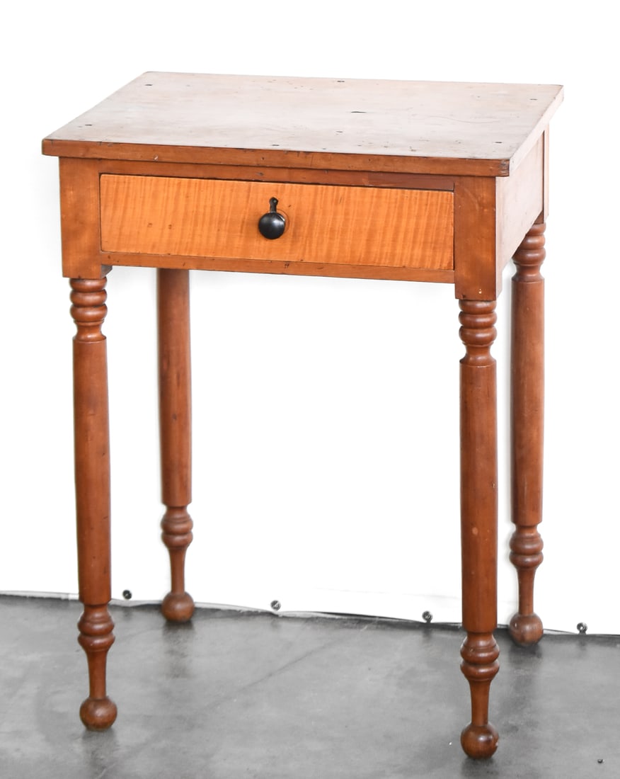 AMERICAN SHERATON STYLE TIGER MAPLE SINGLE-DRAWER STAND: An American Federal period Sheraton style cherry and tiger maple single-drawer stand with ring-and-ball legs on spool feet, from mid 19th century. There is a note attached to the bottom that reads "Th