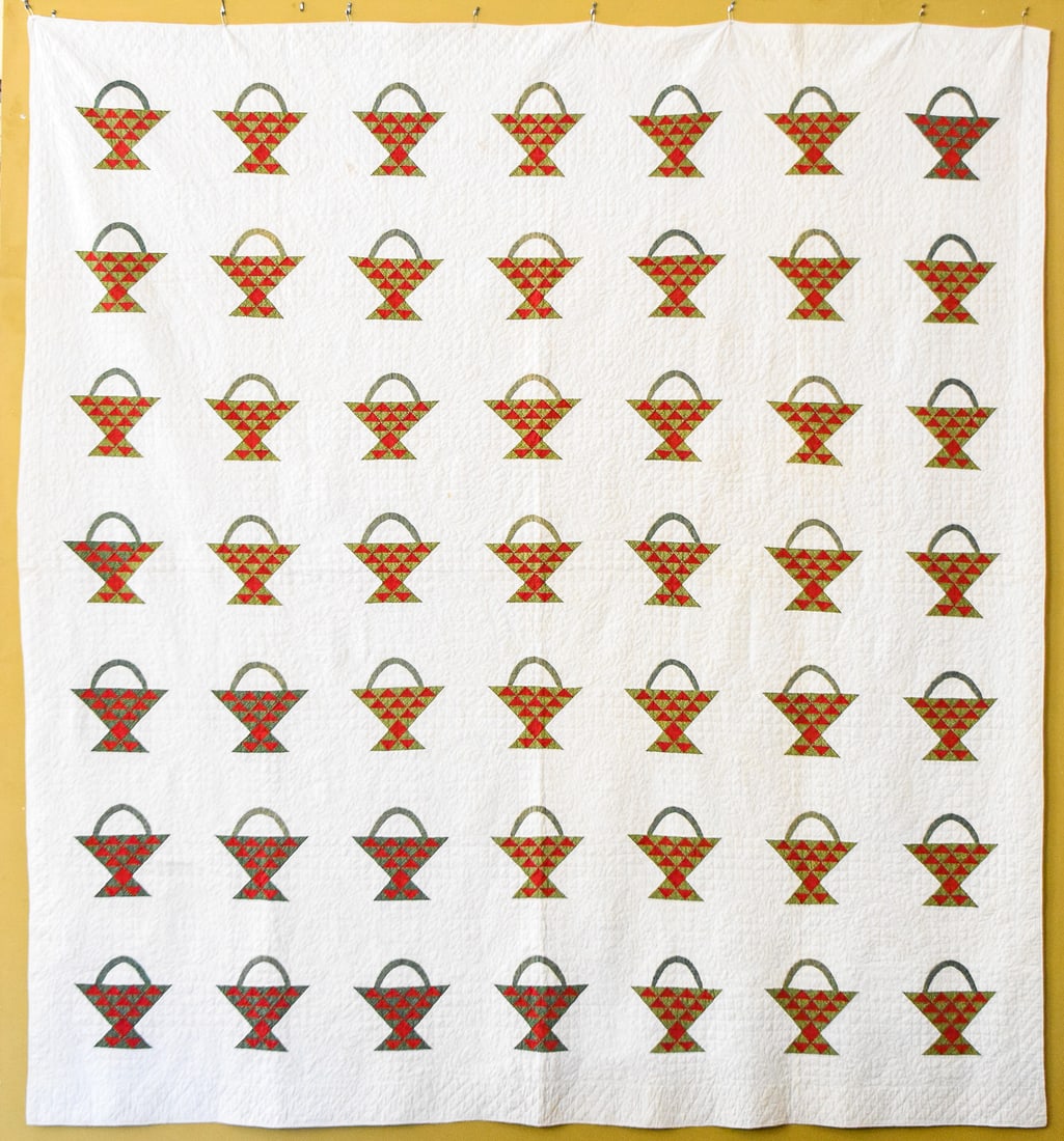 FLOWER/FRUIT BASKET QUILT: This quilt from the late 19th century features a red and green basket pattern on a white background. It measures approx. 92" H x 84" W x 0.5" D.