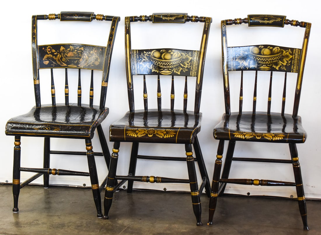 SET OF THREE WOODEN HITCHCOCK STYLE CHAIRS: This lot includes three similar but ultimately unique wooden chairs from the 19th century made in the style of Lambert Hitchcock. They are unmarked but feature stencil-painted harvest motifs in gold.