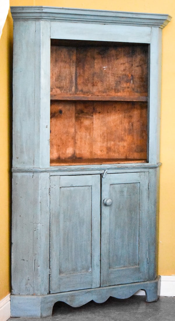 BLUE PAINTED PINE CORNER CABINET: A vintage blue painted pine corner cabinet with shelves above, two doors below, and a decorative finish on the bottom. It measures approx. 72" H x 44" W x 21" D.
