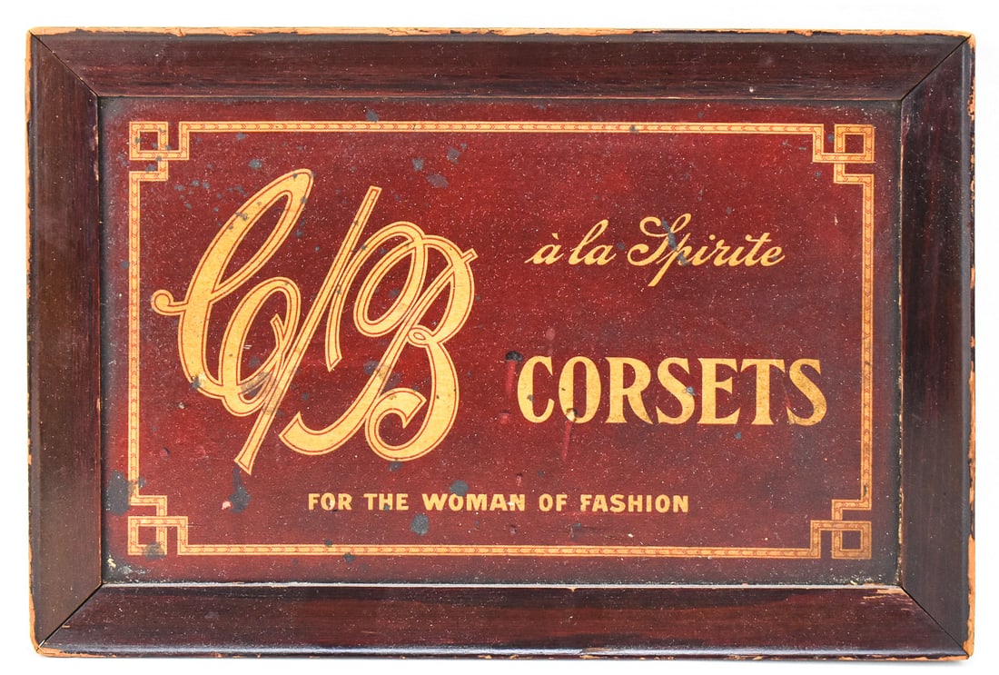 C/B A LA SPIRITE CORSETS WOOD ADVERTISING SIGN: A C/B a la Spirite Corsets painted framed wood advertising sign, early 20th century. The sign has a slogan painted on the bottom "For The Woman of Fashion". The sign measures approx. 9" H x 13.5" W x