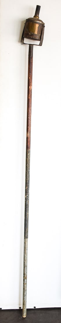 PRIMITIVE PARADE TORCH: A mid-late 19th century parade torch also known as a campaign lamp. It has a swiveling fuel canister at the top and is on a long wooden pole which measures approx. 75" H.