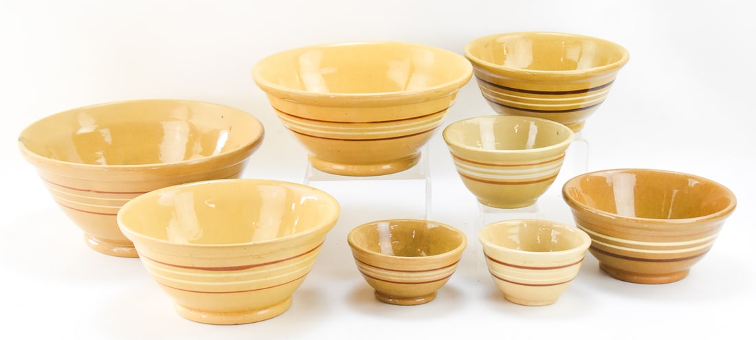 ASSORTMENT OF EIGHT BANDED YELLOW WARE BOWLS: MCCOY POTTERY AND OTHERS: This lot includes eight assorted yellow ware bowls decorated with multi-colored banding, from the early-mid 20th century. One of the smaller bowls is made by the Nelson McCoy Pottery Company and