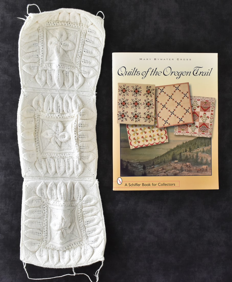 RAISED LEAF PATTERN KNITTING SAMPLE AND SIGNED "QUILTS OF THE OREGON TRAIL": This lot includes a raised leaf knitting sample and a 2007 Mary B. Cross signed "Quilts of the Oregon Trail" book with personal notes of provenance. The book measures approx. 0.5" H x 8.5" W x 11" D.