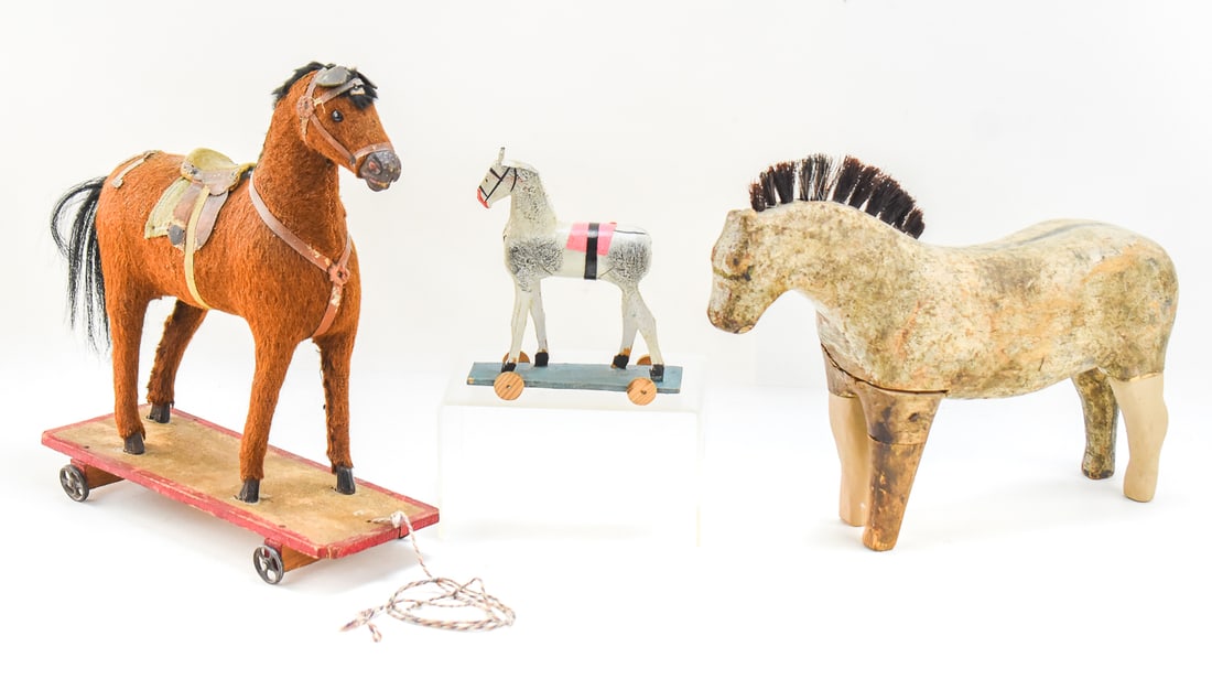 TRIO OF FOLK ART TOY PUSH & PULL HORSES: A trio of folk art toy horses which includes two German pull horses, the larger one covered in mohair. The lot also includes a wooden horse figure that measures approx. 9.5" H x 13" W x 5" D.