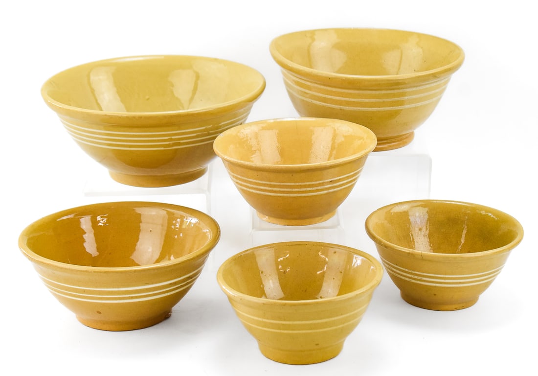 ASSORTMENT OF SIX WHITE-BANDED YELLOW WARE BOWLS: This lot includes six assorted yellow ware bowls decorated with white colored banding, from the early-mid 20th century. Three of the bowls are medium in size, and three of them are smaller bowls. The 