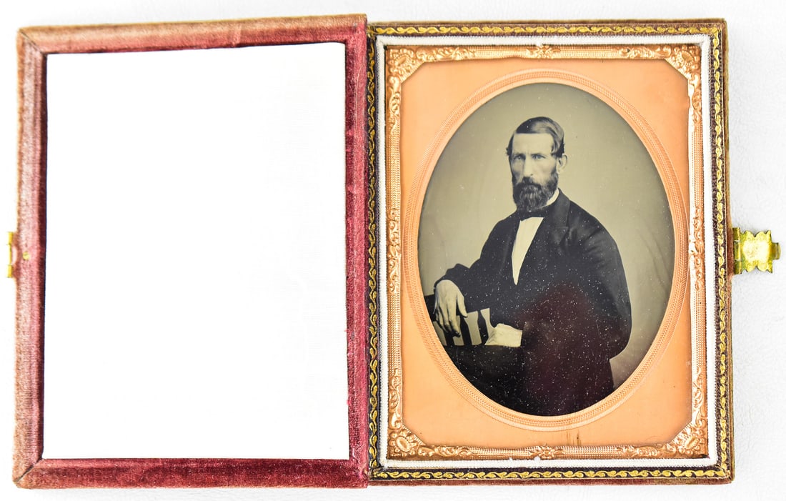TINTYPE OF A MAN IN ARMCHAIR: This tintype is of a man seated in an armchair c. 1850s. The case is 1/4 plate size made of velvet with a white silk liner c. 1854. This case measures approx. 5" H x 4" W x 1" D when closed.