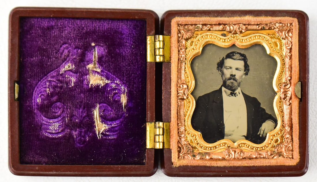 MINIATURE DAGUERREOTYPE; UNION CASE: A daguerreotype of a bearded gentleman inside a miniature Union case, mid-19th century. When closed the case measures approximately 2" H x 2" W x 0.5" D.