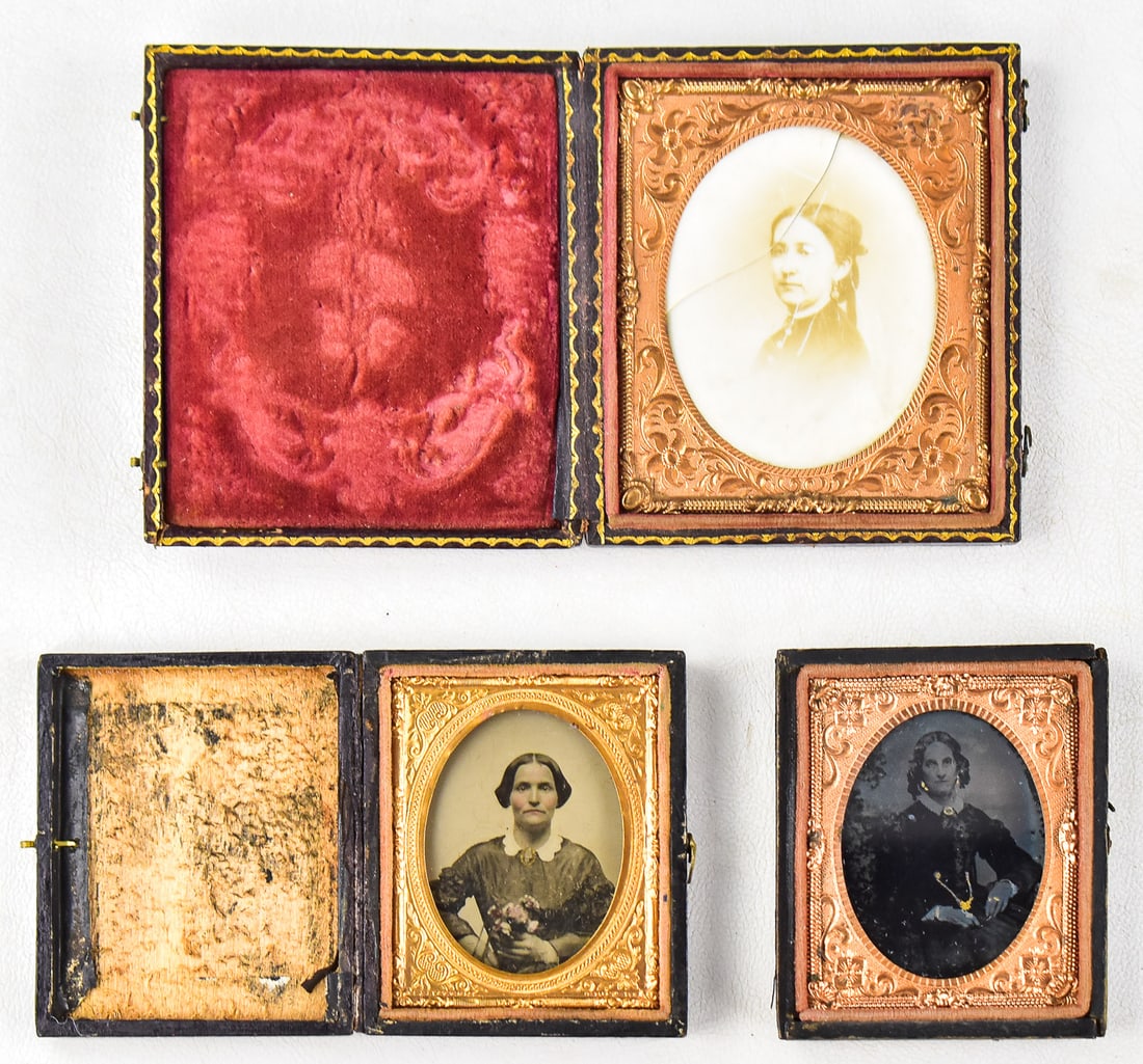 AMBROTYPE TRIO DEPICTING WOMAN: This lot includes three ambrotypes depicting women, circa 1850s: 1/6th plate of a woman's face in sepia colors in a leather case with floral designs, 1/9th plate of a woman holding a bouquet of