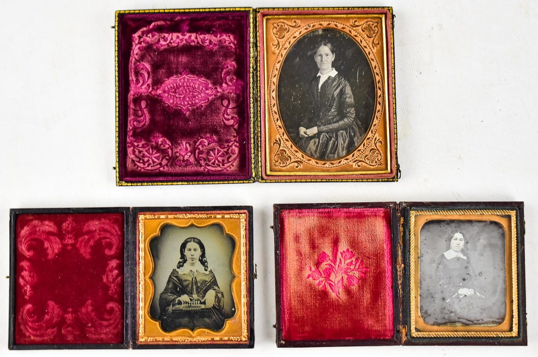 AMROTYPE TRIO OF SEATED WOMAN: Photo one is an older woman in black in 1/6 plate leather case with a homestead theme and red lining. Photo two is a woman with an instrument in a 1/4 plate leather case with a red lining. Photo