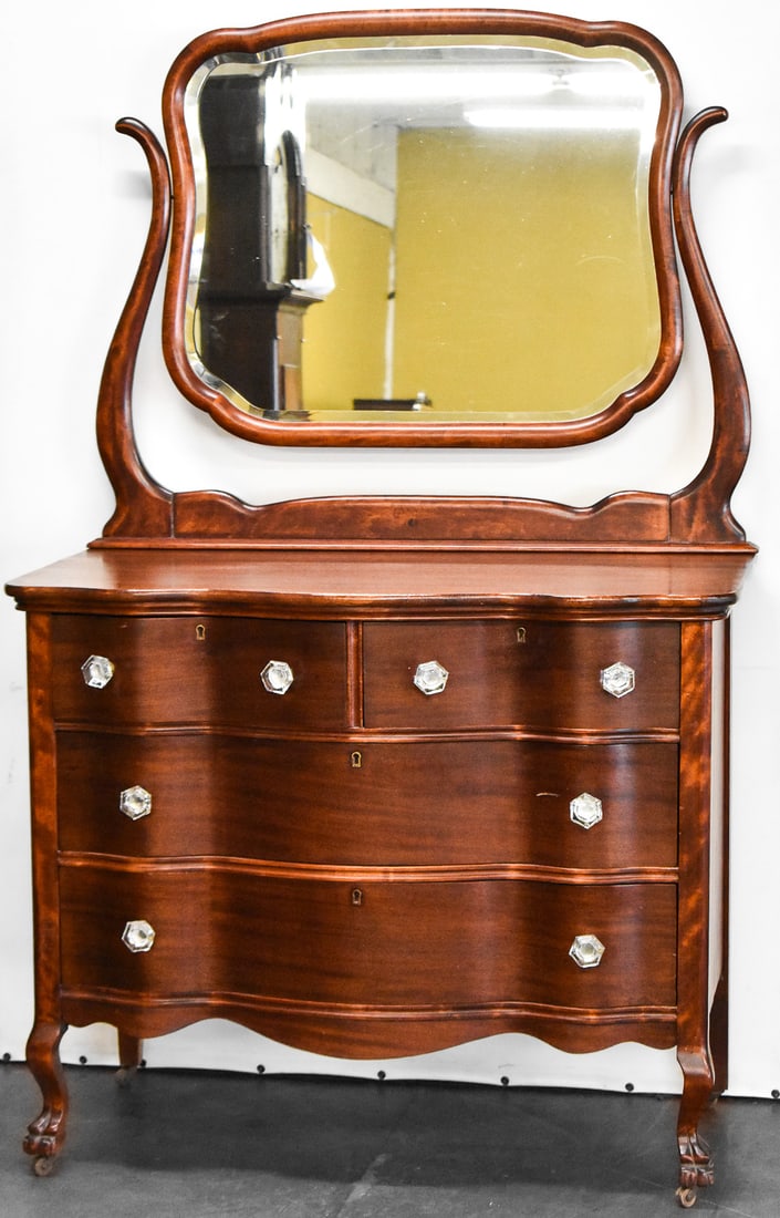 MAHOGANY SERPENTINE DRESSER WITH WISHBONE MIRROR: This dresser is crafted of mahogany wood and glass knobs. It has a serpentine front and wishbone mirror on top. Dresser measures approx. 67" H x 42" W x 20" D.