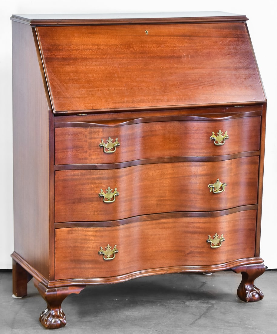 CHIPPENDALE STYLE SLANT FRONT SECRETARY DESK: This desk is a reproduction on the Chippendale desks of the 18th century. Manufactured in the mid 20th century with a serpentine front, talon feet, brass hardware and a drop front desk. This desk