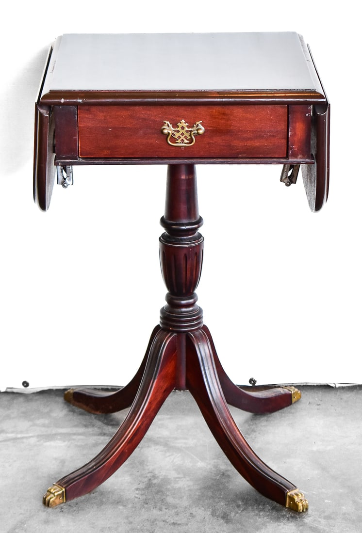 DUNCAN PHYFE STYLE DROP LEAF PEDESTAL SIDE TABLE: This side table is crafted of mahogany wood with metal hardware and was reproduced in the mid 20th century. When folded open the table measures approx. 24.5" H x 30.5" W x 16" D.