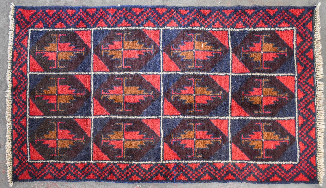 AFGHAN BALUCHI WOOL RUG: An Afghan Baluchi hand-knotted wool rug featuring geometric panels, mid-20th century. The item measures 32" H x 57" W x 0.5" D.
