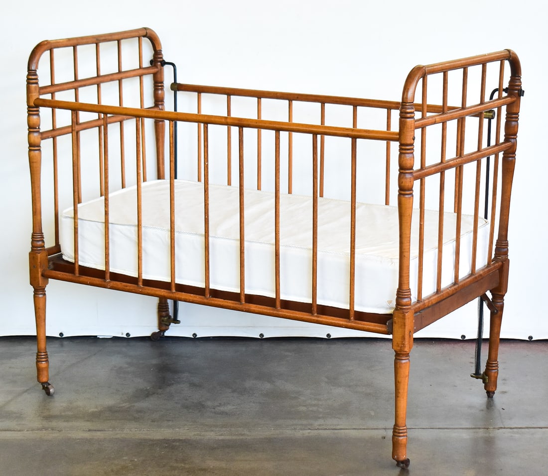 OAK DROP-SIDE CRIB: An oak drop-side crib with cast iron latches now, for decorative purposes only due to child safety laws; circa late 19th-early 20th century. The item measures approximately 37" H x 45" W x 23.5" D.