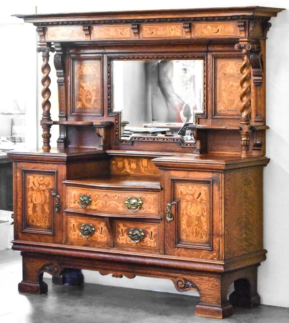 RENAISSANCE REVIVAL SIDEBOARD: A Renaissance Revival oak sideboard with fruitwood marquetry inlay and features barley twist columns, brass hardware; late 19th century. The item comes apart in two pieces, when fully assembled the