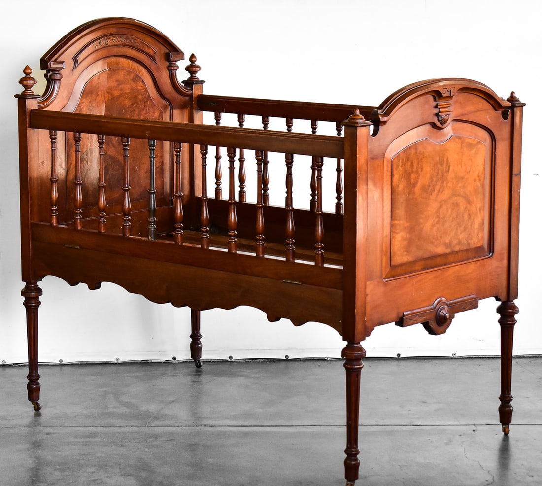 VICTORIAN WALNUT BABY CRIB: A Victorian walnut drop-down baby crib for decorative purposes only due to child safety laws, circa late 19th-early 20th century. The item measures approximately 49.5" H x 53" W x 32.5" D.