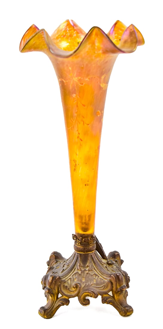 ART NOUVEAU AMBER GLASS TRUMPET VASE: This vase has amber glass with enameled floral decorations on a cast metal base. This is circa early 20th century and measures approximately 12.5" H x 5.5" W x 5.5" D.