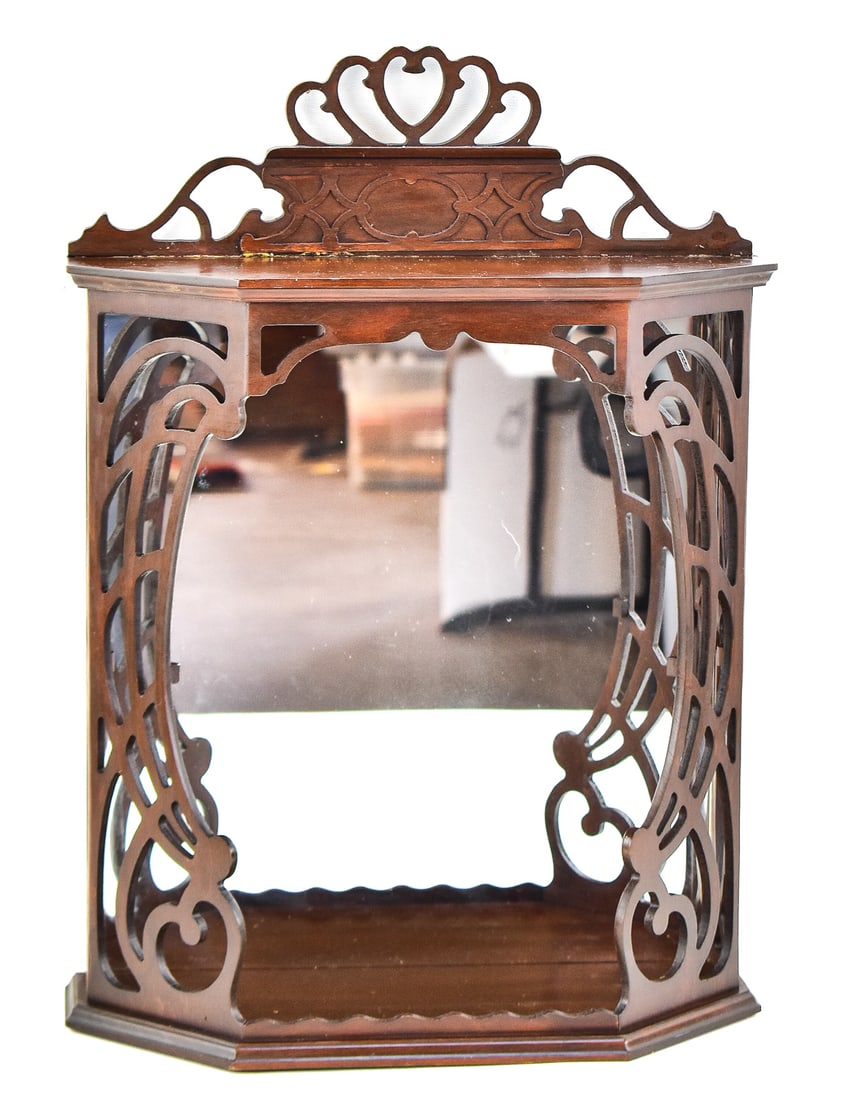 WALL MIRROR-BACK DISPLAY SHELF, BUTLER SPECIALTY COMPANY: A wall-hanging mirror-back display shelf with a top crest and intricate wood fretwork, made by the Butler Specialty Company. The back is stamped "Butler Style# 136". This shelf measures approximately