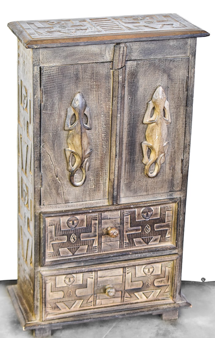 HAND-CARVED TEAK CABINET, INDONESIA: A hand-carved teakwood cabinet with traditional Indonesian motifs such as lizard carvings on the doors and figural carvings. These cabinets originate from Java, Indonesia. The cabinet measures approxi