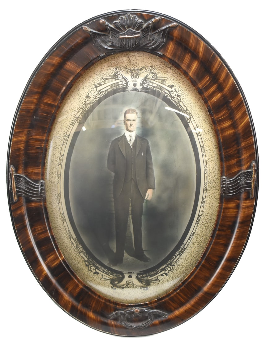 VICTORIAN PORTRAIT IN A PATRIOTIC BUBBLE GLASS FRAME: This Victorian full-body portrait of a man is in a oval frame with bubble glass. The wooden frame has been stained to look like tiger maple and features patriotic, molded accents including the America