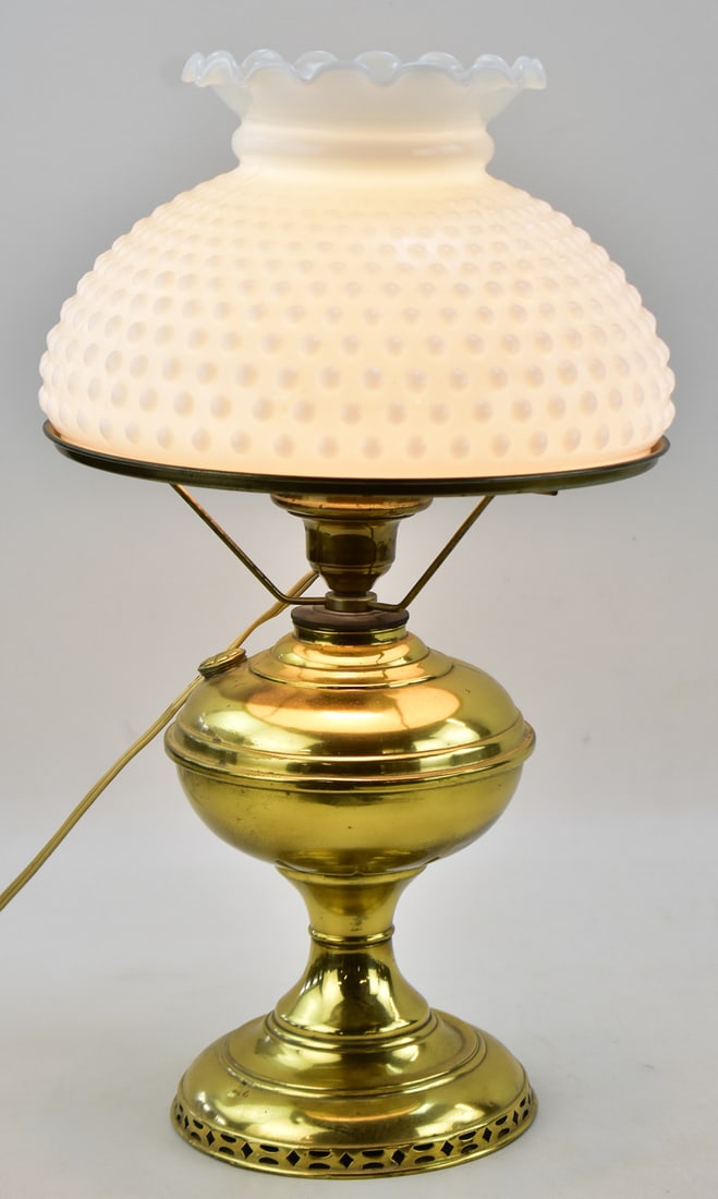 ELECTRIFIED BRASS HURRICANE STYLE PARLOR LAMP: Lamp is topped with a white hobnail milk glass shade. The lamp has been modified to run on electricity vs oil. The lamp is from the mid 20th century and measures approximately 19" H x 10" W x 10" D.