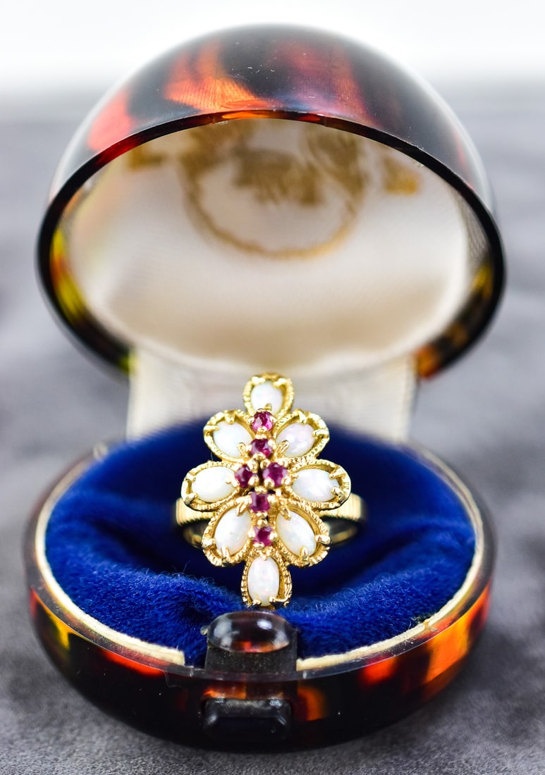 14KT GOLD OPAL AND TOPAZ COCKTAIL RING: Ring size is 6.5. Ring is made of 14kt yellow gold with eight opal pedals and six ruby red topaz gems. Ring measures approx. 1" H x 0.5" W x 1" D.