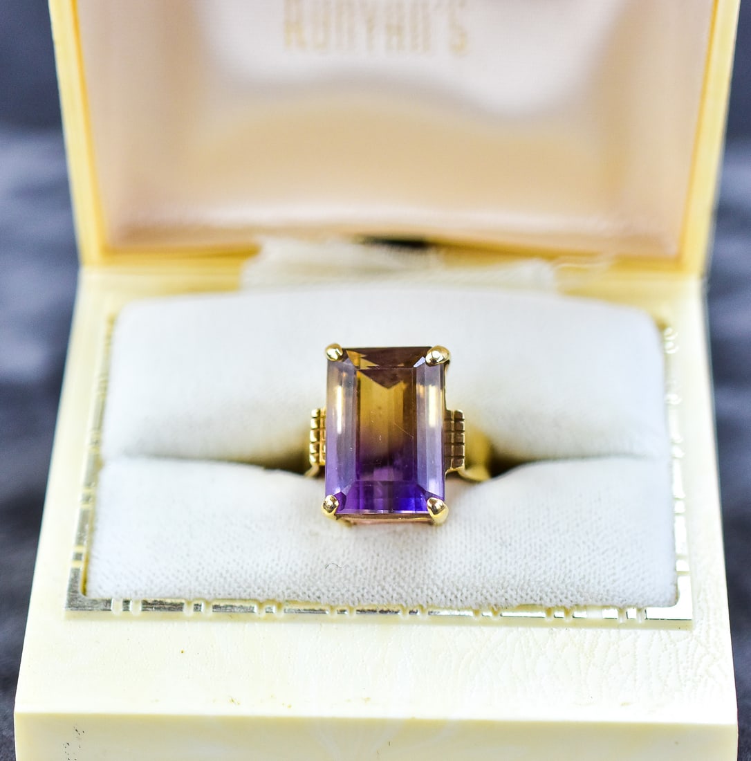 14KT GOLD & EMERALD CUT TOPAZ SOLITAIRE RING: Ring size is 6 and manufactured by Seattle Company. Ring is made of 14kt yellow gold with a topaz center stone with an emerald cut. Ring measures approx. 1" H x 0.5" W x 0.5" D.