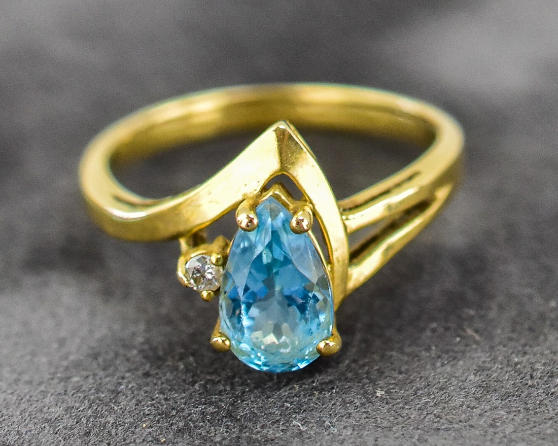 T&C 10KT GOLD RING: Ring size is 5. Ring is made of 10kt yellow gold with both a pear cut blue topaz and small diamond. Ring measures approx. 1" H x 0.5" W x 0.5" D.