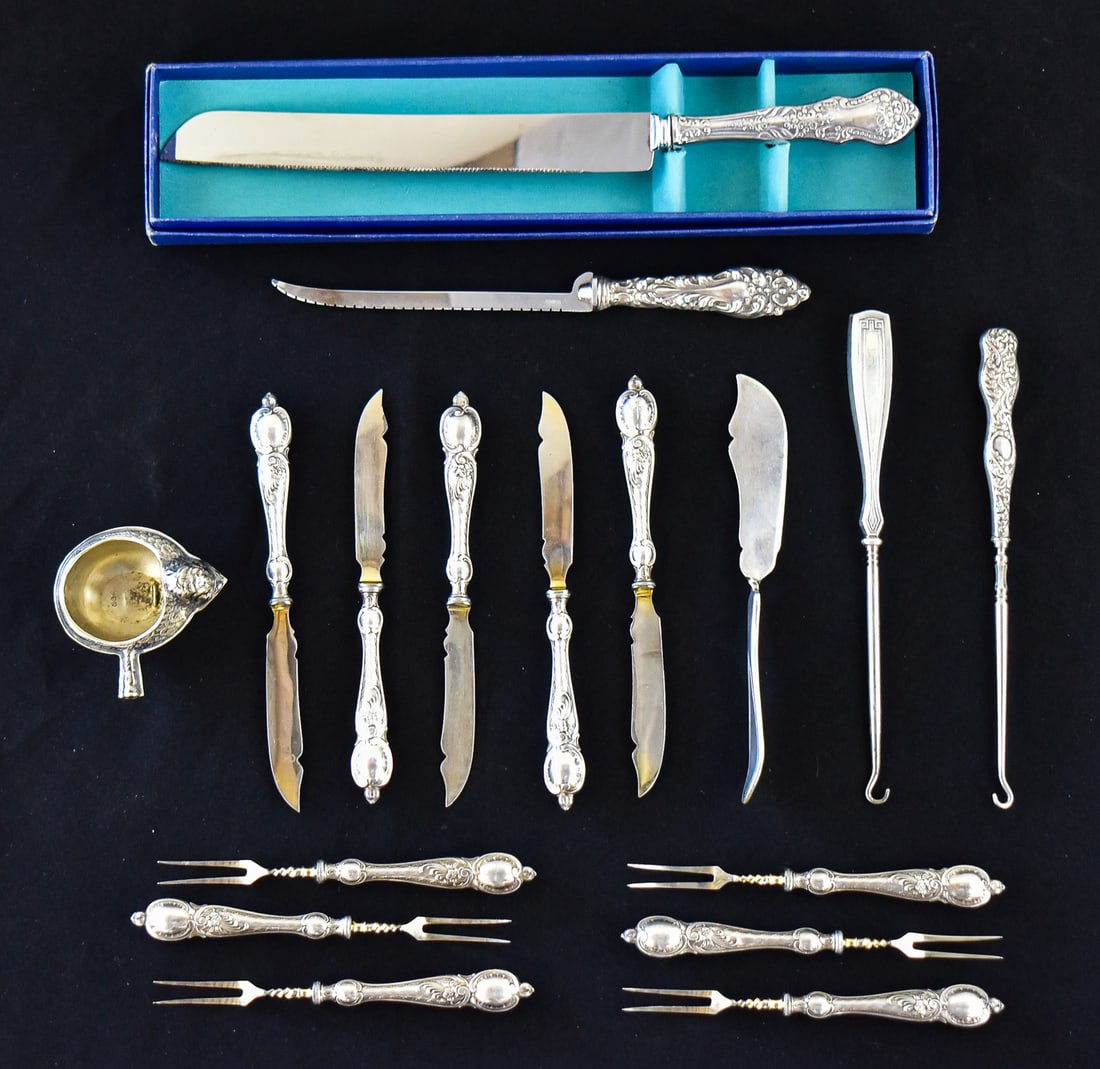 ASSORTMENT OF SILVER-PLATE AND STERLING HANDLED FLATWARE: An assortment of silver-plated and sterling handled flatware, produced in the late 19th/ early 20th centuries. The lot includes a Prill serrated knife, an American Sterling Company butter knife, a