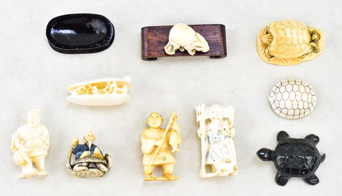 ASIAN STONE AND BONE CARVED FIGURES: Nine Asian carved figures made out of various stones and bone, and two small wooden display stands. The figures include turtles, a rabbit, a small garden scene in a shell-shaped carving, and Netsuke