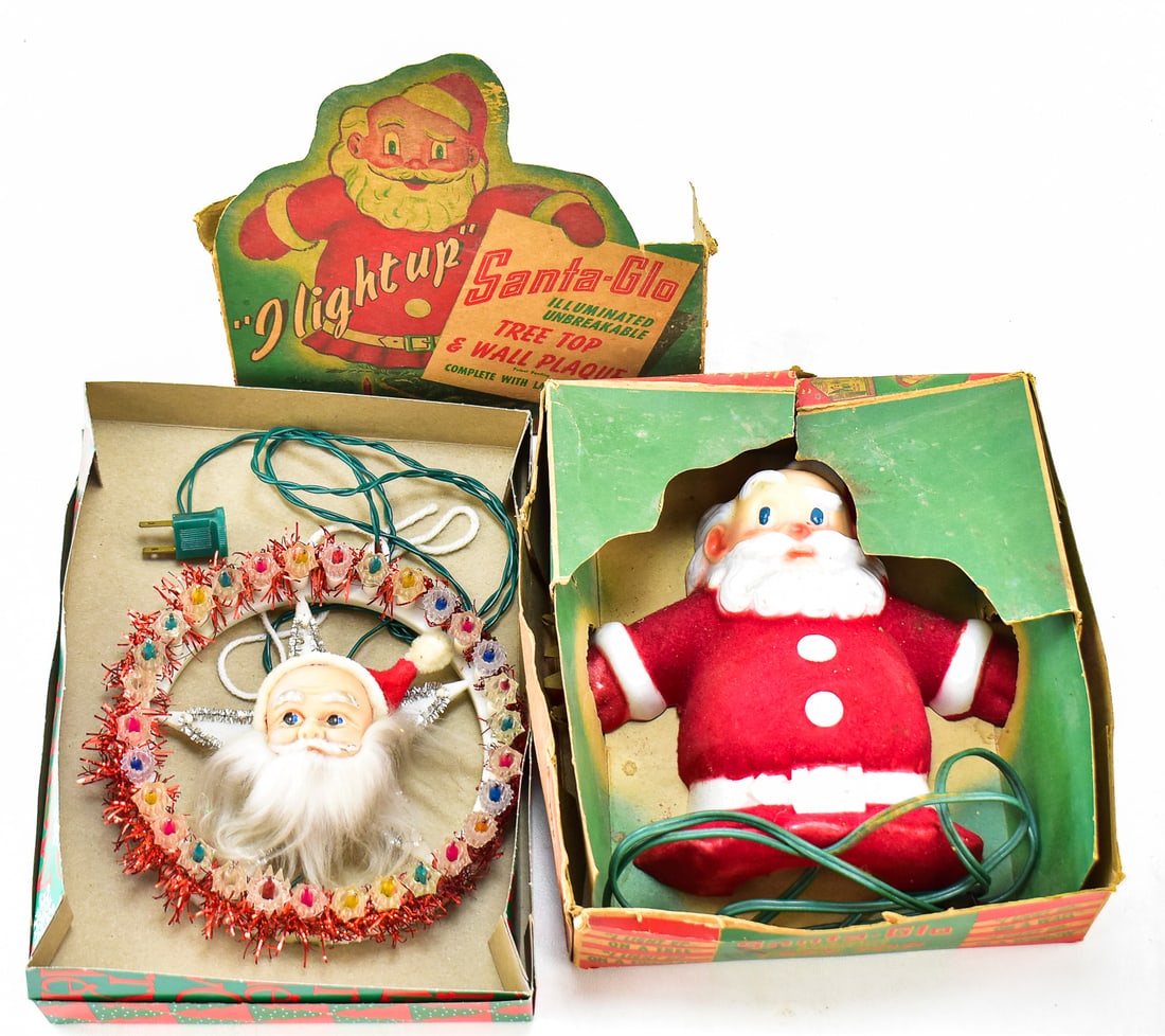 DUO OF MID-CENTURY LIGHTED CHRISTMAS SANTA WALL PLAQUES: A 1960s lighted Santa Claus face tinsel wreath and a 1950s "Santa Glo" lighted tree topper or wall plaque measuring 8" H x 8" W x 3"D and is in the original box.