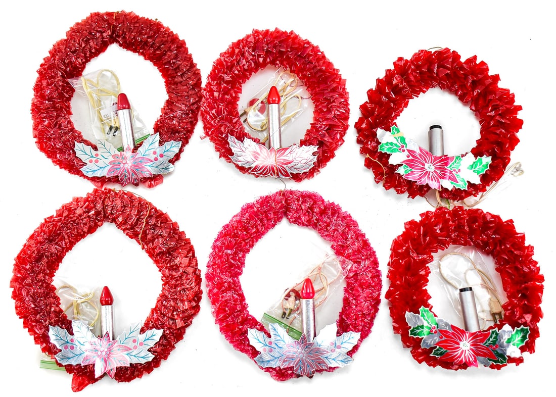 6 RED CELLOPHANE CHRISTMAS WREATHS: This lot has six cellophane Christmas wreaths with an electric candle in the center. They have a cardboard poinsettia accent underneath the candles. Designed to be window decorations from the