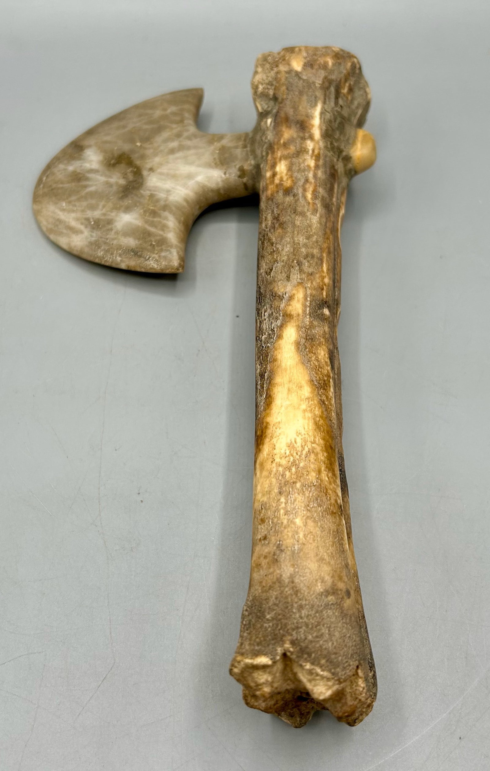 An Early Stone Axe with a Bone Handle: A 4 by 5 inch stone blade mortised through a 9 inch bone handle. As found- with expected wear for its age.