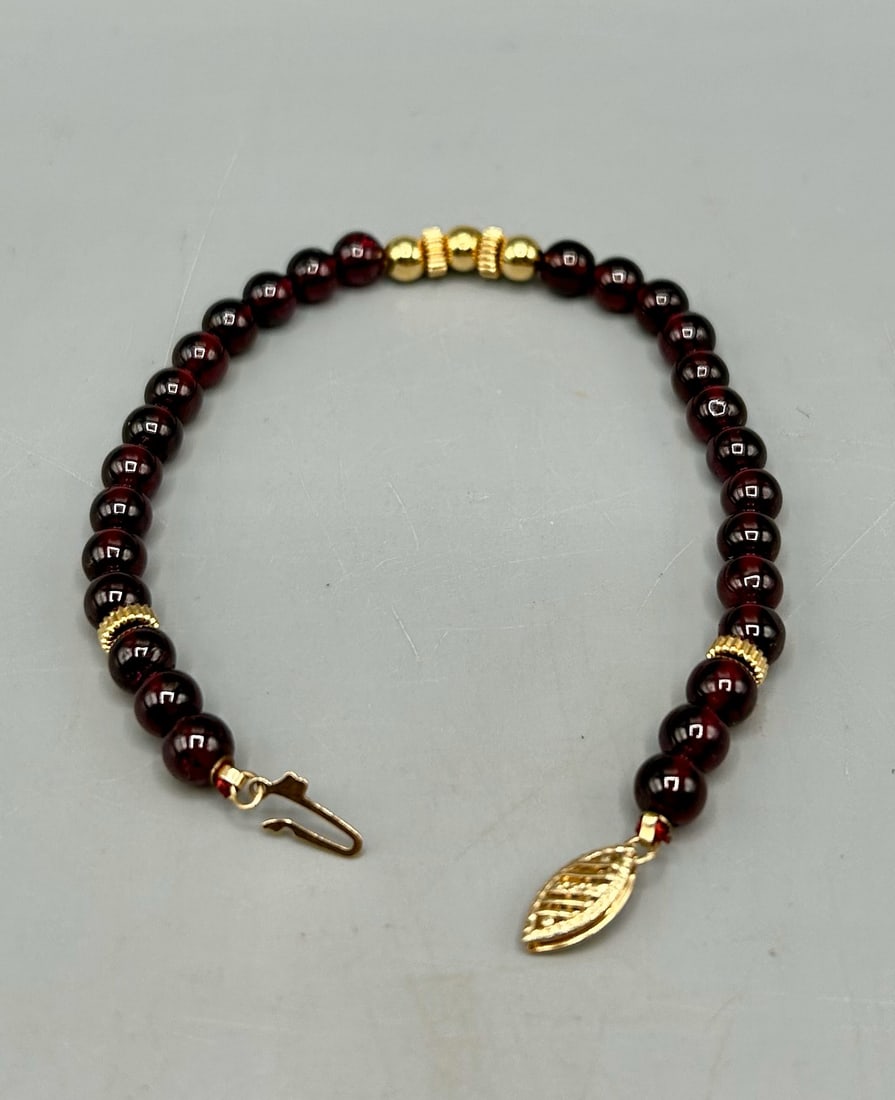 A Garnet and 14 kt Gold Beaded Bracelet: A 7 inch garnet and gold bracelet, stamped 14 k on the insert half of the clasp. In good condition.